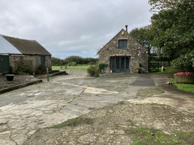 The stone cottage with its glazed double front doors, reached across a wide, level concrete yard.