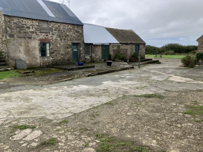 The stone games room buildings beside a large concrete yard with uneven, patched surfaces and low steps along the building fronts.